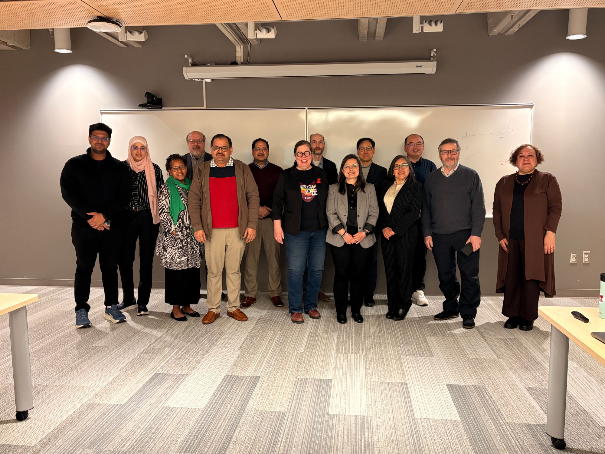 Workshop participants and organizers standing together for a group photograph in front of a whiteboard.